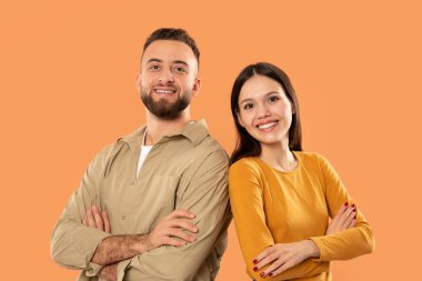 Bir erkek ve bir kadın yan yana duruyorlar, ileriye bakıyorlar. Günlük giysiler giyiyorlar ve sohbet ediyor gibi görünüyorlar.