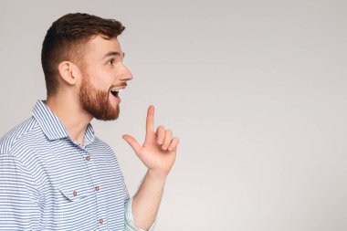 Heyecanlı genç adamın iyi bir fikri var ve bu konuda mutlu. Gri stüdyo arka planı, panorama, kopyalama alanı.