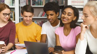 Uluslararası Üniversite Öğrencileri Takımı Kütüphanede Öğrenim görüyor, dizüstü bilgisayarla çalışırken eğleniyor