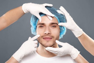 Estetik Kozmetoloji kavramı. Doktorlar elleri eldiven yakışıklı genç adamın yüzüne dokunmadan, closeup