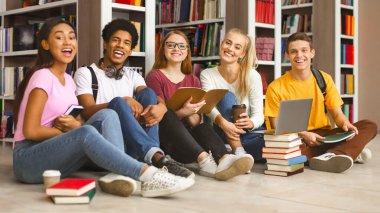 Takım çalışması ve eğitim. Birlikte sınavlara hazırlanıyor çeşitli genç sınıf arkadaşları grubu, kütüphane katta oturan ve gülen, boş alan