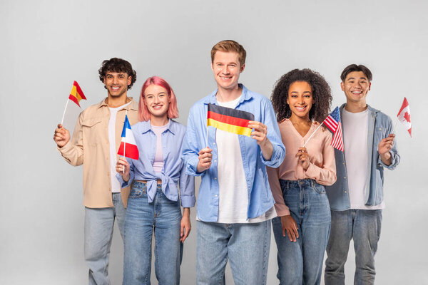 A Group of Five Young Adults, Each Holding a Different National Flag, Stand in Front of a White Background. They Are All Smiling and Appear to Be Proud of Their Respective Countries