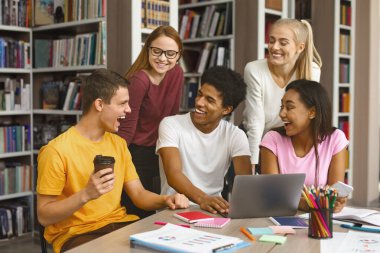 Liderlik kavramı. Kütüphanede proje yapan çokuluslu ekip öğrencileri, fikirlerini ifade eden akıllı adam