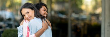 Şehir caddesinde tanıştıktan sonra kucaklaşan neşeli çoklu etnik kız arkadaşlar, birbirini görmekten mutlu olan iki güzel genç kadın, sarılıp gülümseyen, dışarıda buluşmaktan keyif alan, boşluğu kopyalayan iki genç kadın.