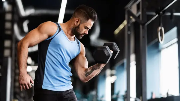 stock image Muscular sportsman with strong body lifting heavy dumbbell, empty space