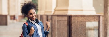 Kutlama yapan neşeli Afrikalı Amerikalı Öğrenci Sınav Sınavı 'nı geçti ve üniversite binasının önünde sırt çantasıyla kameraya gülümsüyor. Başardım, Eğitim Başarı, Uzayı Kopyala