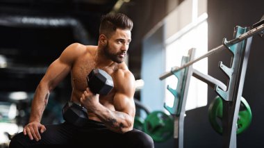 Çıplak gövde ile güçlü kaslı adam dumbbells ile egzersizler yapıyor, spor salonunda egzersiz, boş alan
