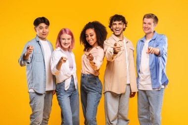 Beş genç yetişkinden oluşan çeşitli bir grup sarı bir arkaplan önünde duruyor, hepsi de yüzlerinde kocaman bir gülümsemeyle kameraya bakıyor. Hepsi sıradan giyinmiş, kot pantolon ve gömlek giyiyorlar..