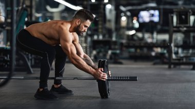 Atlet onun halter üzerinde ağırlık plakaları ekleyerek, spor salonunda yaptığı halter egzersiz için hazırlanıyor, boş alan