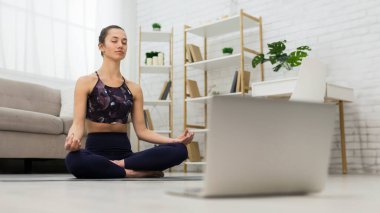 Kendi kendini öğrenme. Oturma odasında yoga online eğitim dizüstü bilgisayar kullanan kadın