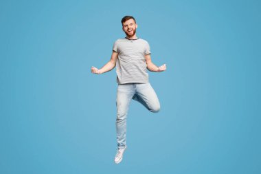 Başarımızı kutluyoruz. Heyecanlı Genç Millennial Kızıl Saçlı Adam Mavi Stüdyo Arkaplanda Zıplıyor ve Hareketleniyor