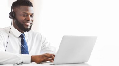 Genç afro iş danışmanı, kulaklıklı, dizüstü bilgisayarında istemciye e-posta yazıyor, boş alan