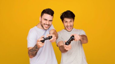 İki Avrupalı birlikte video oyunu oynuyorlar, yüzleri odaklanma ve zevk gösteriyor.