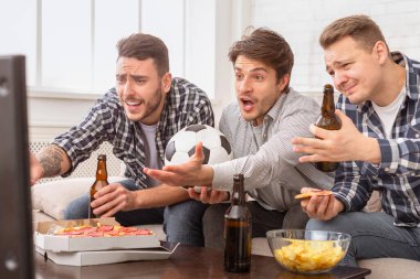 Avrupalı erkekler futbol maçı izleyerek, erkekler arasındaki dostluk ruhunu yansıtan yoğun duygular ifade ederler.