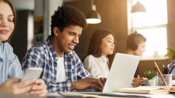 Stock image Intelligent afro guy studying with laptop and books at library, preparing for final exams