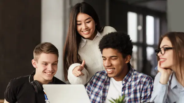 stock image College students using laptop in library, studying together for school assignment