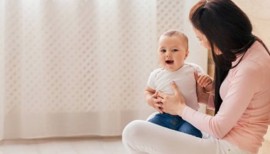 A woman sitting down and cradling a baby in her lap. The baby appears content and secure in her arms, while the woman gazes down at the child with a soft expression. clipart