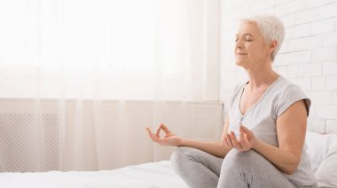 Yoga yaparken, evde, yatakta lotus konumda boş alanı meditasyon kadın kıdemli