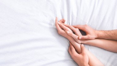 Bu resim beyaz bir yatakta birbirine dolanmış bir çiftin ellerini gösteriyor. Bu da samimiyet ve bağlantının kesildiğini ve uzayı kopyaladığını gösteriyor.