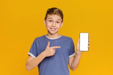 Duygusal genç çocuk beyaz mobil ekran ve gülümseyen işaret, turuncu stüdyo arka plan