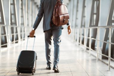 Havaalanında bavullu tanınmayan bir yolcu görülüyor. Ortam odaklı ve profesyoneldir. Seyahat, iş ve arka plan konularını vurgulayan modern bir havaalanı ortamı vardır.