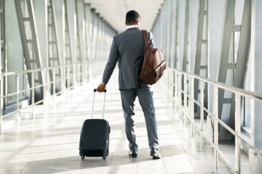 Bavullu bir şirket yolcusu havaalanında görülmüş. Ortam odaklı ve profesyoneldir. Seyahat, iş ve arka plan konularını vurgulayan modern bir havaalanı ortamı vardır.