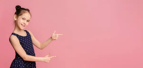 stock image Cute little girl smiling and pointing aside, showing something at blank space, pink panorama background