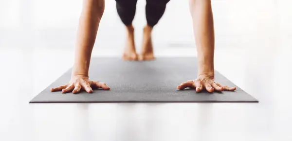 stock image Cropped of woman maintains balance and focus as she performs a yoga pose on a gray mat. Her bare feet and hands are pressed against the surface, suggesting strength and flexibility