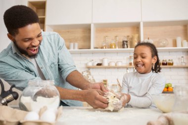 Afro-Amerikan baba ve kızı pasta yapmaktan zevk alıyor, bir anlığına da olsa mutfakla aile bağlarını paylaşıyorlar.