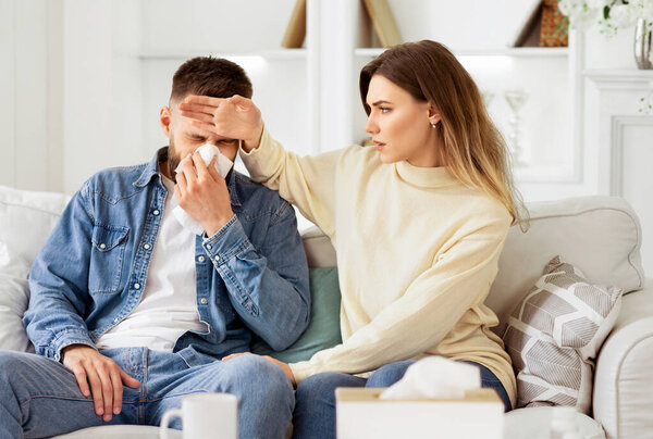 Woman Taking Care Of Her Ill Husband, Touching His Forehead