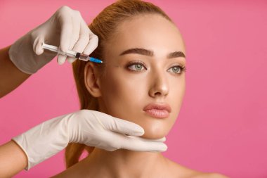 Kozmetoloji kavramı. Genç kadın gözleri, pembe arka plan yakın güzellik enjeksiyonu alıyorum