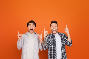 Two lively european men enjoying a playful moment, pointing upwards, which signifies their optimistic friendship and bonds as mates clipart