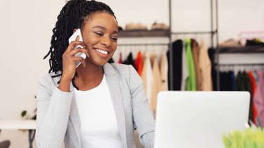 Afrika kökenli Amerikalı bir iş kadını bir masada oturmuş, cep telefonuyla bir telefon görüşmesi yapıyormuş. Önünde evrak işleri varken tartışmaya odaklanmış gibi görünüyor..