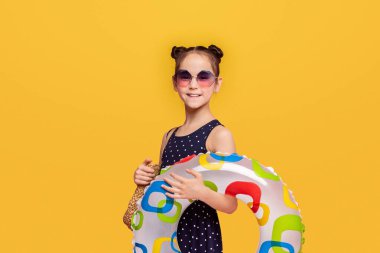 Yüzmeye gidiyorum. Renkli şişme yüzük tutan küçük kız, pembe stüdyo arka plan