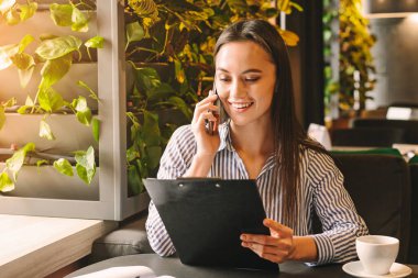 Yetenekli kadın planlama çalışma programı ve not defteri arıyor, kafede telefonda konuşurken, boş alan