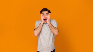 Wow. Açık ağız ile şok erkekler turuncu arka plan üzerinde kamera bakıyor