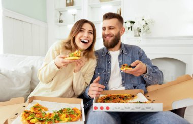 Ev hafta sonu. Neşeli Çift Tv önünde pizza yiyor, komedi filmi izliyor