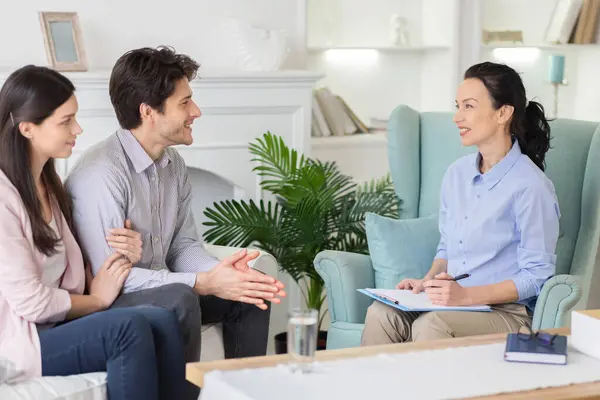 stock image In a soothing therapy room, a young couple consults with a lady psychologist, seeking advice to strengthen their relationship in a supportive and empathetic environment.