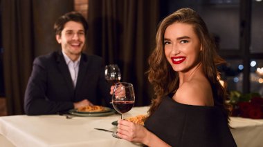 Güzel, genç bir çift restoranda güzel kıyafetler giyer romantik bir akşam yemeği yer, şarap içerler..