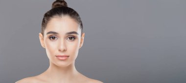 Saçının ortasında düzgün yapılmış bir çöreğin olduğu yakın plan bir kadın yüzü. Özellikleri görülebilir, ve odak noktası saç stili, kopya alanı olan panorama.