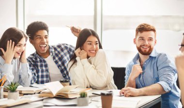 Üniversite yaşam tarzı. Üniversite kütüphanesinde konuşan mutlu öğrenciler, tatilde fıkra anlatırlar.