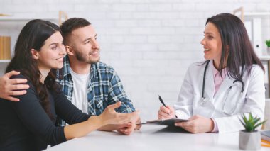 Avrupalı çift, beyaz önlüklü kadın doktorla aynı masada oturuyor. Çift, doktor notlar alırken dikkatle dinleyen bir sohbete daldı.