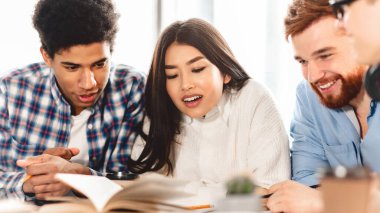 Bilgi ve eğitim kavramı. Kitapları olan mutlu öğrenciler kütüphanede sınava hazırlanıyor.