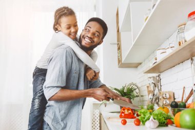 Afrikalı Amerikalı baba ve onun neşeli kızı mutfakta iyi vakit geçiriyorlar, kız babaya arkadan saldırıyor, boş alan.