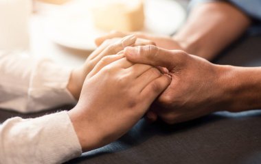 Bir adam ve bir kız bir masada el ele tutuşuyorlar. Erkeklerin eli kızlardan biraz daha büyük. İkisi de gevşemiş ve sohbete dalmış görünüyor.