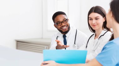 Modern hastane toplantı odasında tartışan sağlık personeli, stajyer ve uygulayıcıların toplantısı