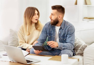 Kanepede oturan bir adam ve bir kadın önlerindeki dizüstü bilgisayara odaklanıyorlar..