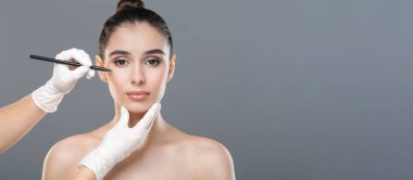 Güzel yarı çıplak kadın estetik ameliyata hazır kadın yüzü doktor eli kalem, gri arka plan, fotokopi alanı olan panorama