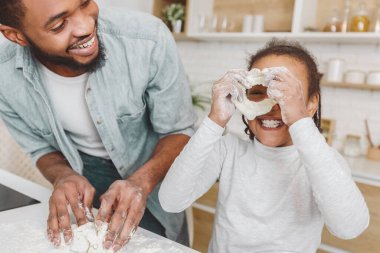 Siyah Neşeli Adam ve küçük kızı mutfakta hamur işi yaparken eğleniyorlar.