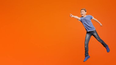 Vay canına, Excited evlat hayran atlama ve boş alan bir yana, turuncu studio arka plana el işaret bak